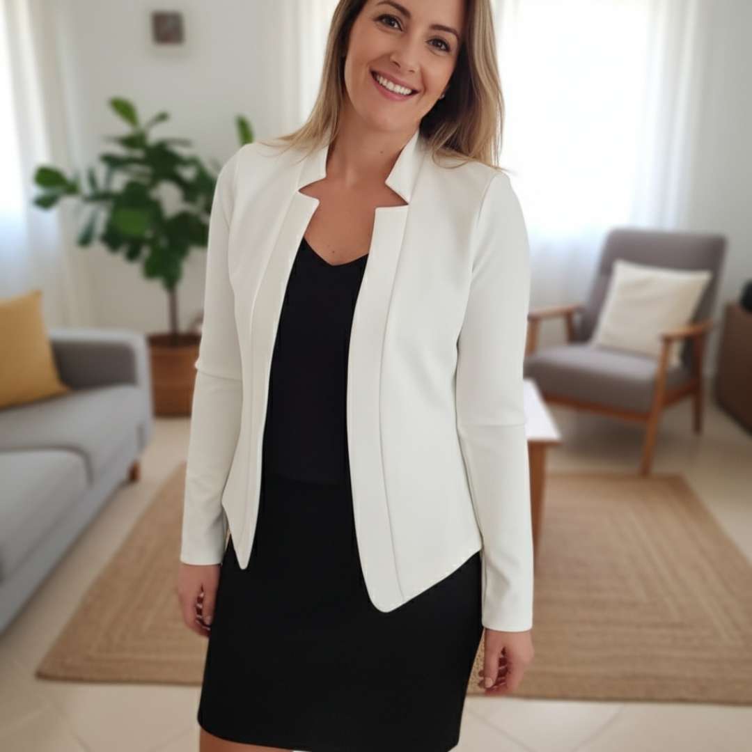 Blazer Feminino Alfaiataria Branco Corte Slim Acinturado aberto sobre vestido preto curto, modelo sorrindo em ambiente de sala