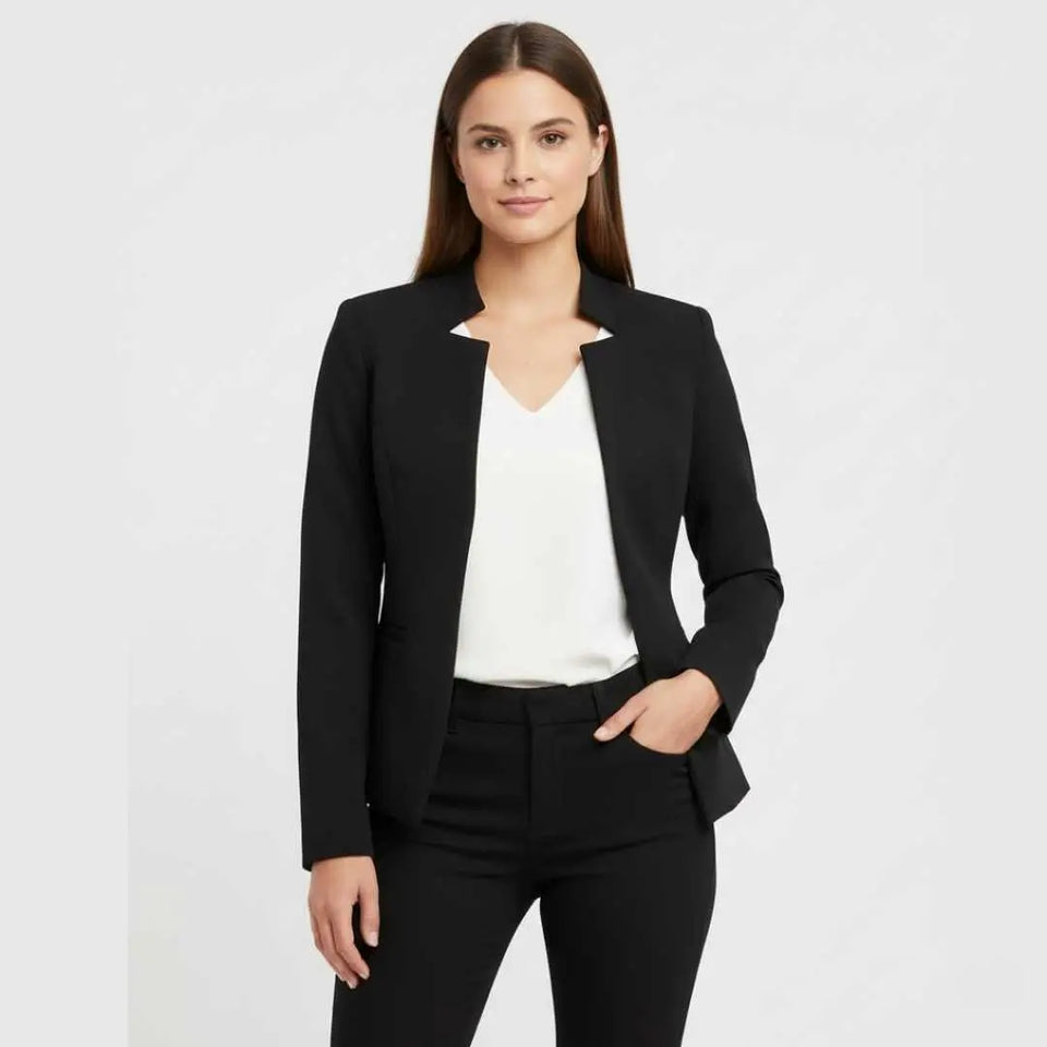 Blazer Feminino Alfaiataria Preto Corte Slim Acinturado visto de frente, aberto sobre blusa branca e calça preta, com a mão no bolso