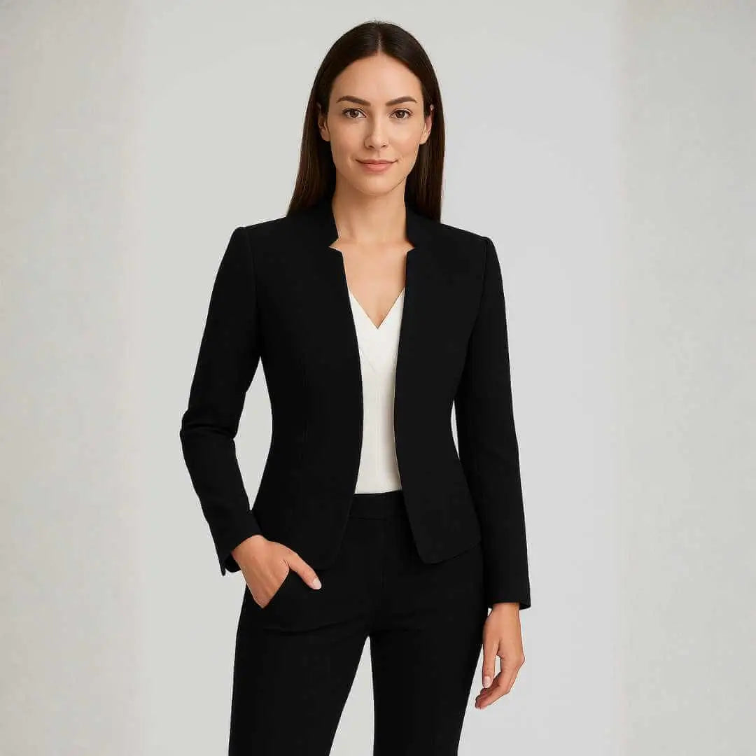 Blazer Feminino Alfaiataria Preto Corte Slim Acinturado em look completo com calça preta, modelo de frente com as mãos nos bolsos