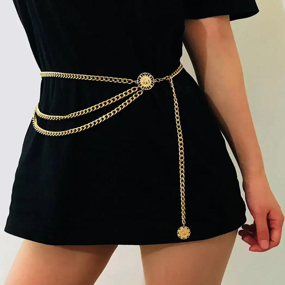 Cinto Feminino Corrente de Metal dourado usado sobre vestido preto curto, com três fios drapeados e pingente medalha