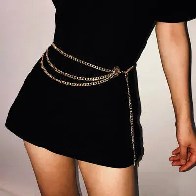 Cinto Feminino Corrente de Metal usado sobre vestido preto, em plano de perfil com a corrente lateral pendente