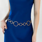 Cinto de Metal Feminino Corrente Dourado usado na cintura sobre vestido azul, com argolas de tamanhos alternados