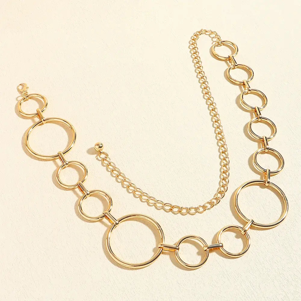 Cinto de Metal Feminino Corrente Dourado disposto em curva, evidenciando a alternância entre argolas grandes e pequenas