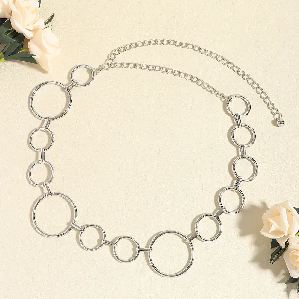 Cinto de Metal Feminino Corrente Prata sobre fundo claro, com rosas brancas ao redor da peça