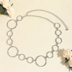 Cinto de Metal Feminino Corrente Prata sobre fundo claro, com rosas brancas ao redor da peça