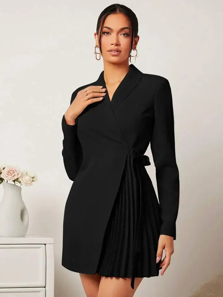 Vestido Blazer Curto Plissado Preto visto de frente, com gola alfaiataria, faixa de amarração e saia plissada lateral