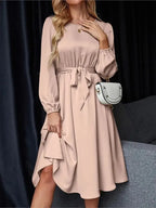 Vestido Casual Midi Manga Longa na cor rosé, visto de frente com faixa amarrada na cintura e bolsa branca a tiracolo
