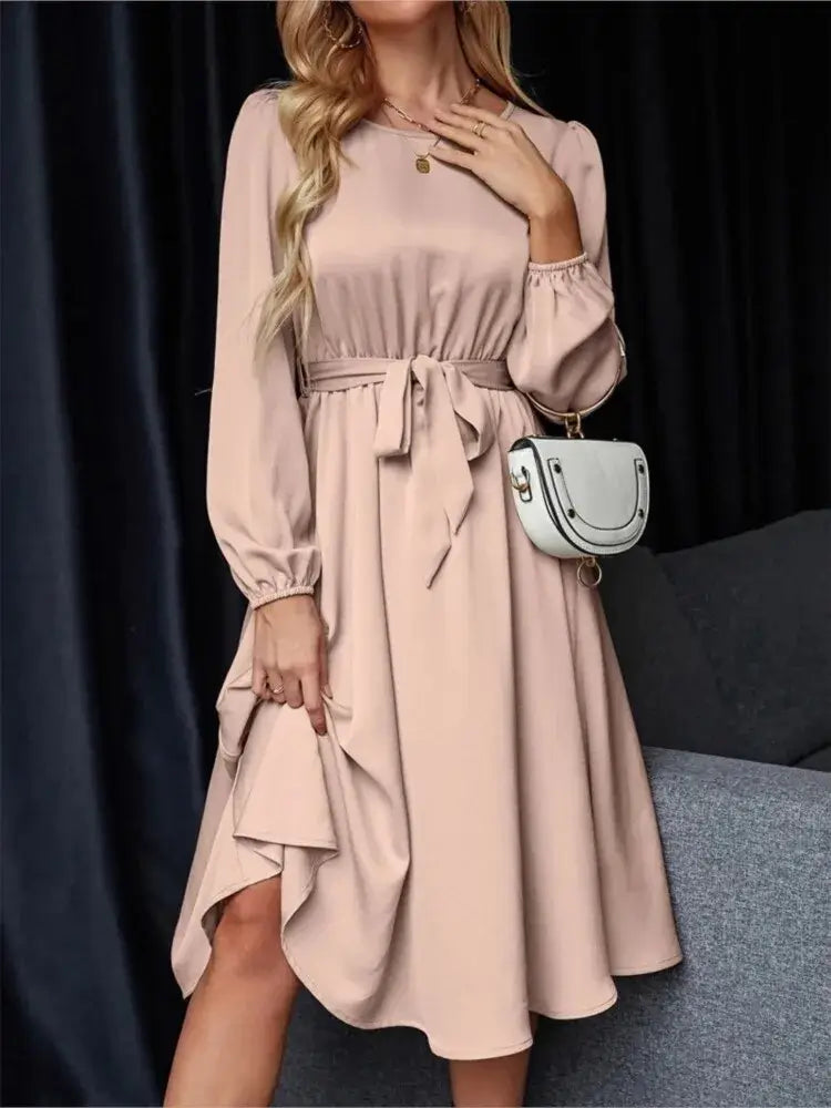 Vestido Casual Midi Manga Longa na cor rosé, visto de frente com faixa amarrada na cintura e bolsa branca a tiracolo