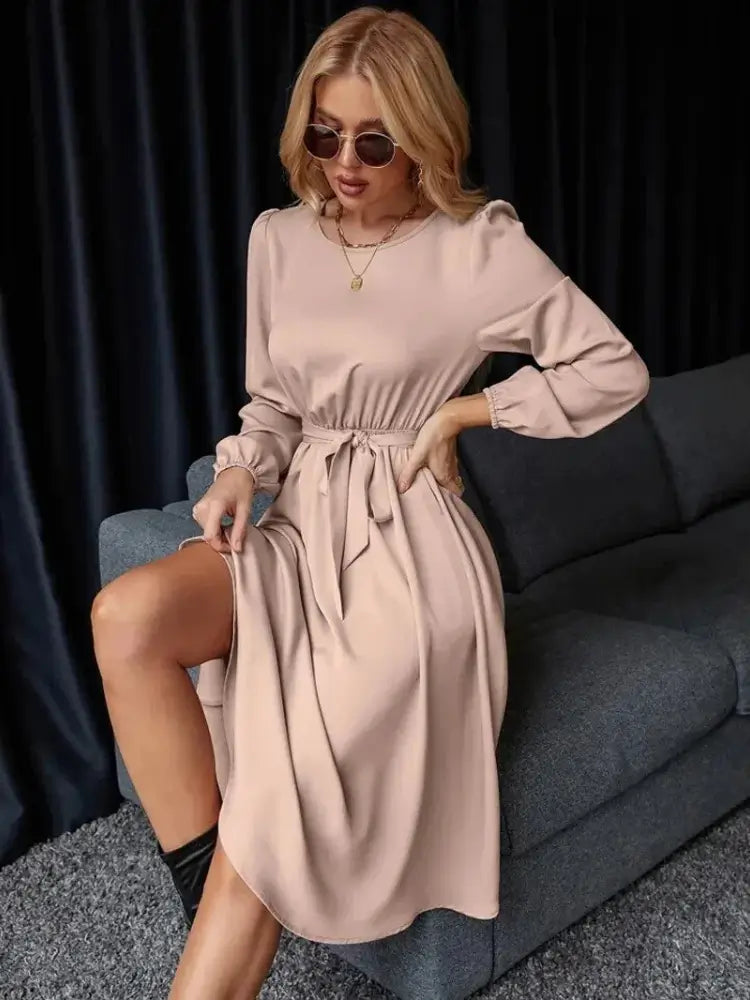 Vestido Casual Midi Manga Longa na cor rosé, modelo sentada no braço do sofá com óculos escuros