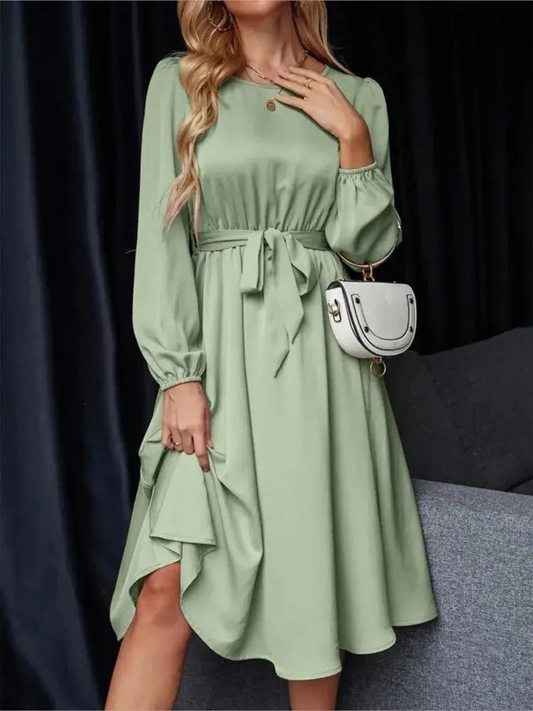 Vestido Casual Midi Manga Longa na cor verde, em plano frontal com bolsa branca a tiracolo e faixa na cintura