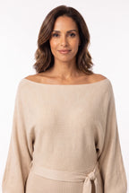 Vestido Curto de Malha com Manga Bufante e Gola Canoa bege em close do busto, destacando a gola canoa caída no ombro