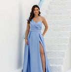 Vestido de Festa Longo Acetinado Um Ombro Só na cor azul serenity, em cena externa com fenda lateral em destaque