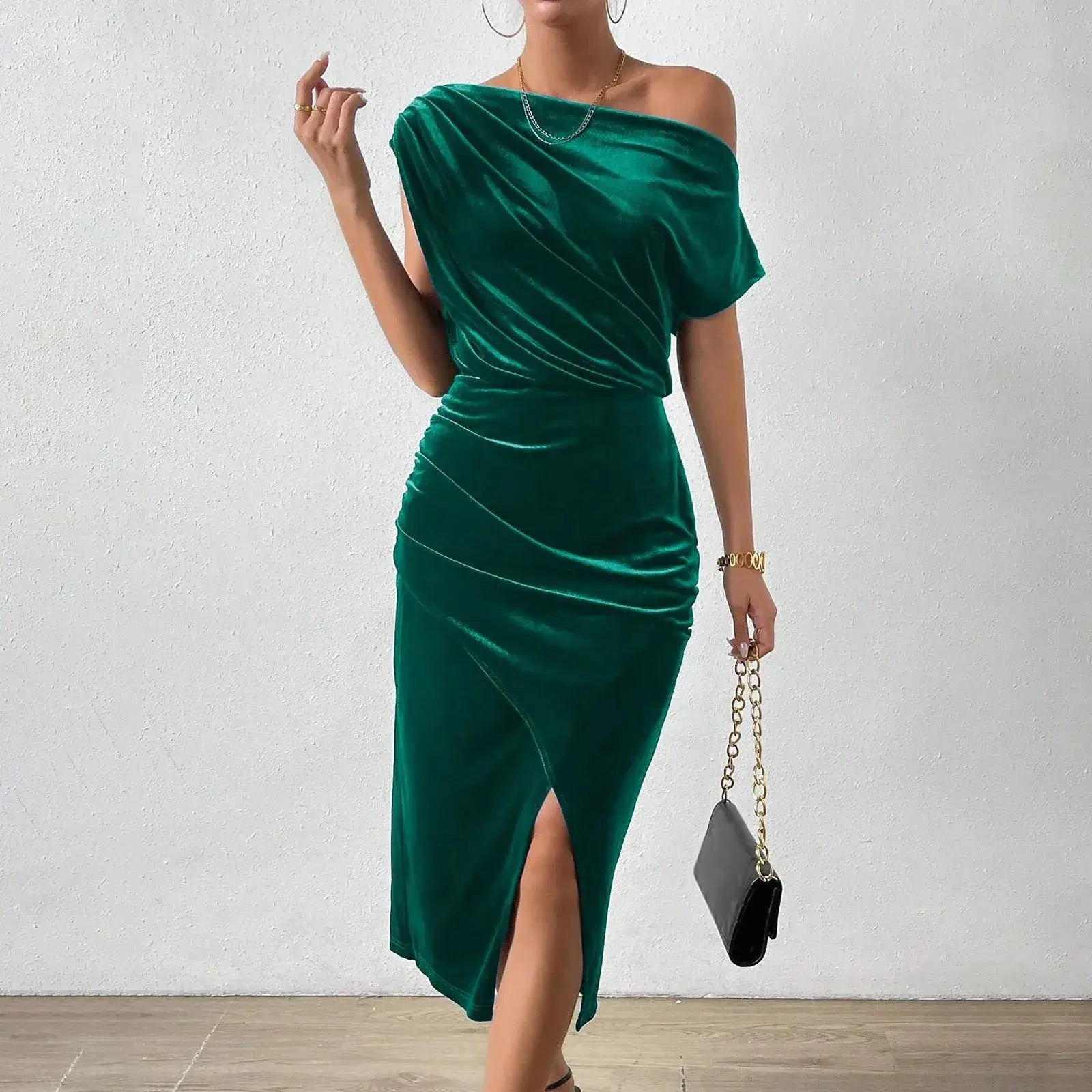 Vestido de Festa Longo de Veludo Sonia na cor verde esmeralda, visto de frente com bolsa preta de alça dourada