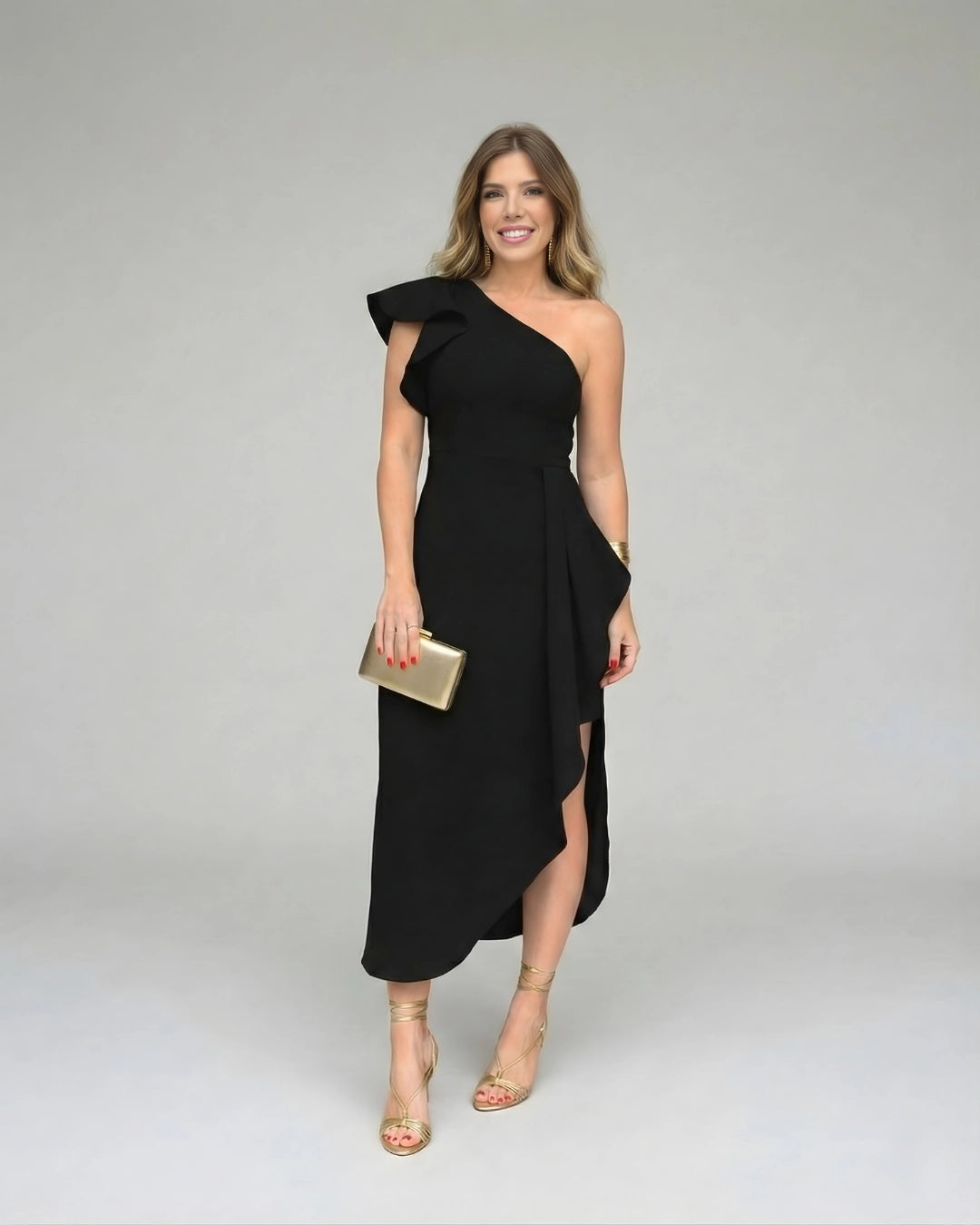 Vestido de Festa Longo Preto Um Ombro Só de frente, com clutch dourada na mão ao lado do corpo
