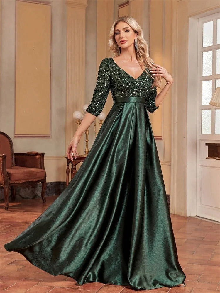 Vestido de Festa Longo Verde em Paetê com Decote V em pose de três quartos, com a mão no bolso da saia