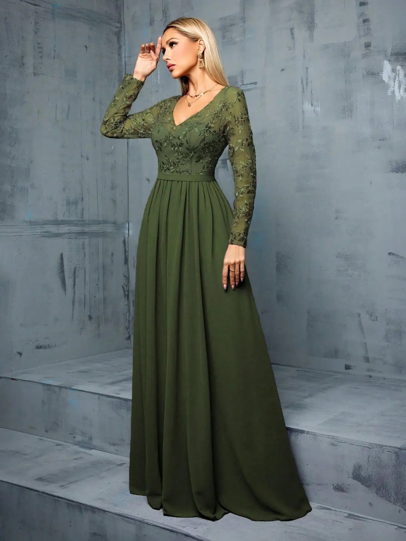 Vestido de Festa Longo Verde Oliva em Chiffon com Bordado Floral em pose de três quartos, com a mão apoiada na testa
