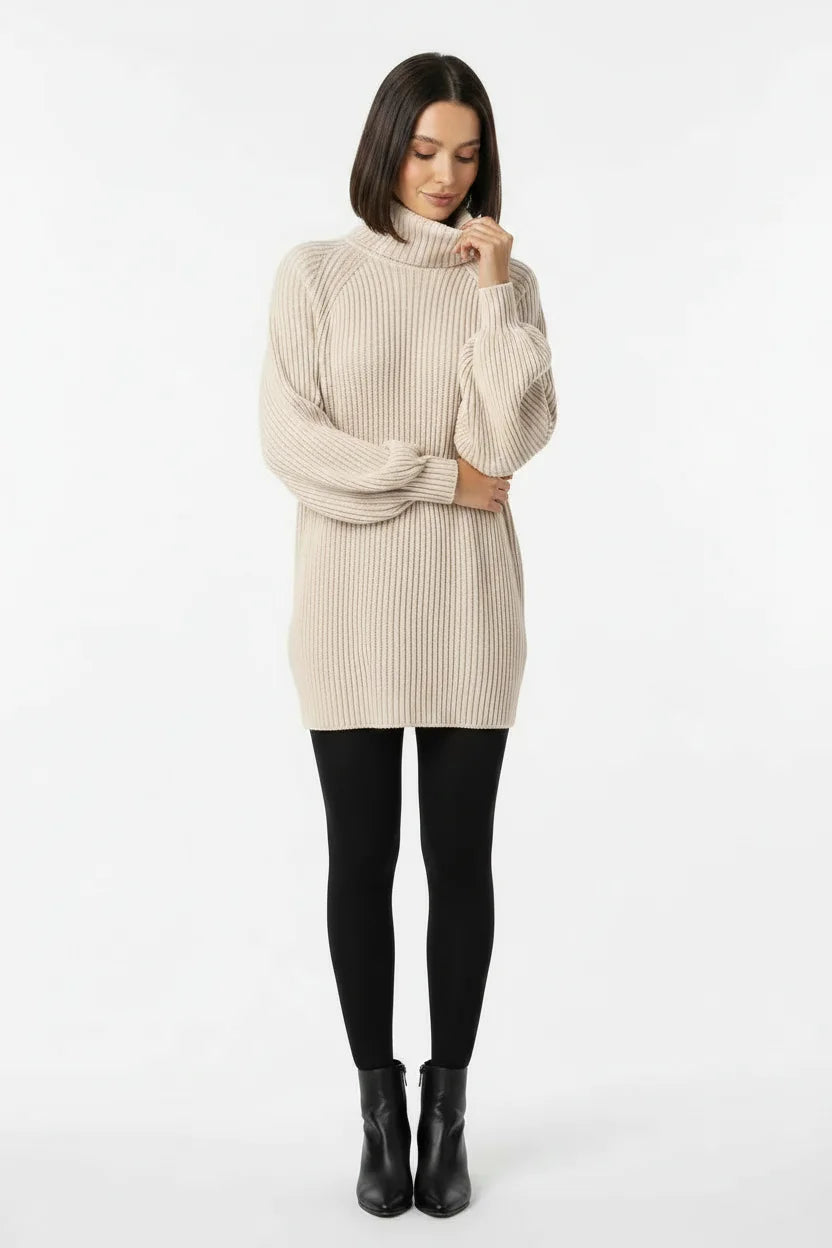 Vestido de Tricot Oversized Gola Alta Bege de frente com a modelo olhando para baixo, mostrando o volume das mangas