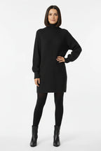 Vestido de Tricot Oversized Gola Alta Grafite visto de frente, com a mão na cintura, meia-calça preta e bota de cano curto