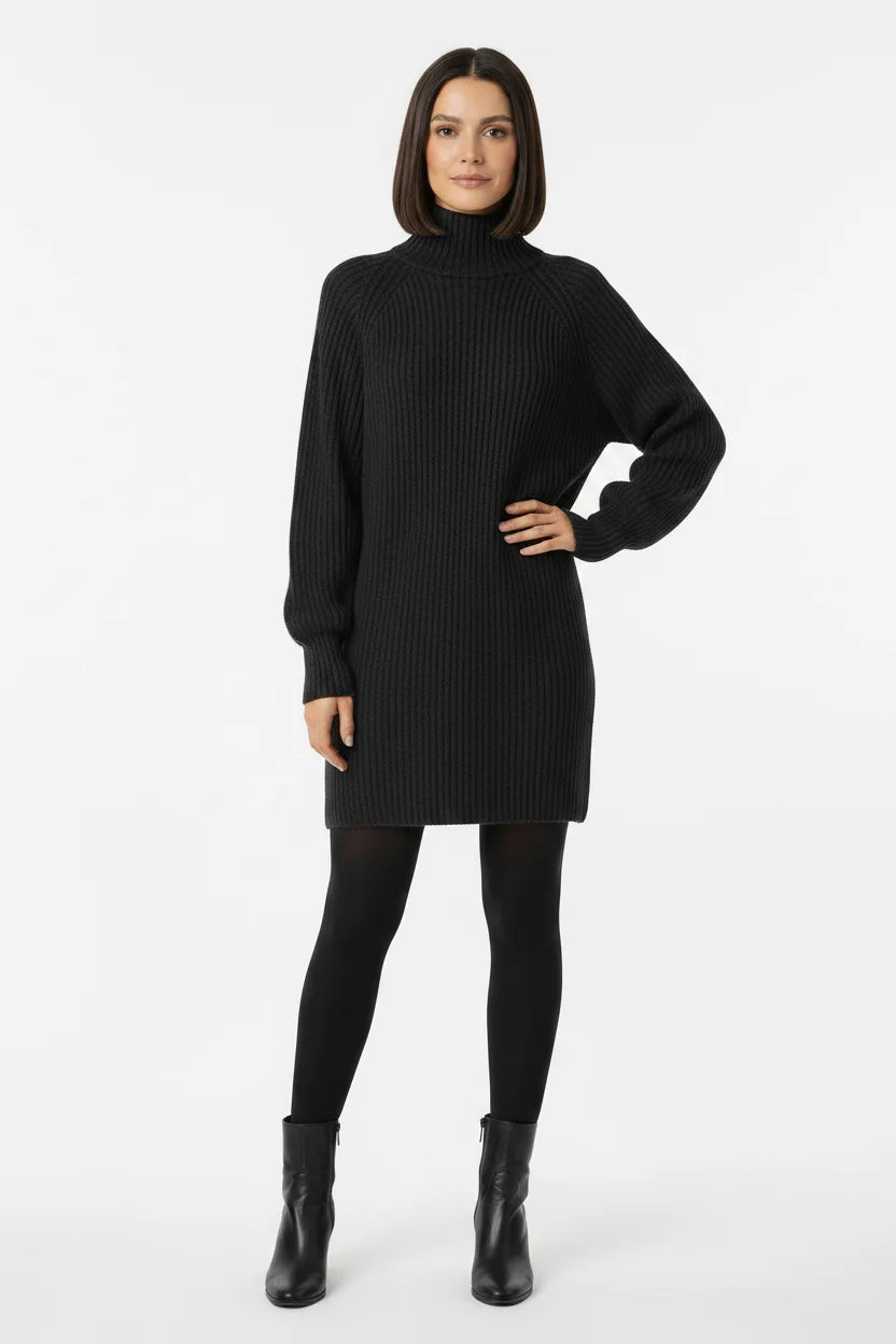 Vestido de Tricot Oversized Gola Alta Grafite visto de frente, com a mão na cintura, meia-calça preta e bota de cano curto