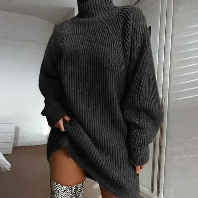 Vestido de Tricot Oversized Gola Alta Grafite em plano aproximado, com a mão puxando a barra e bota estampada