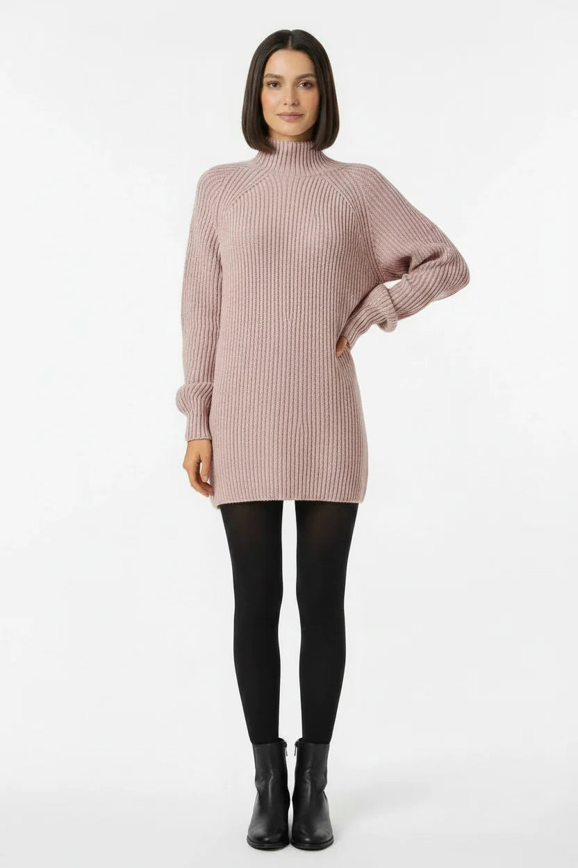 Vestido de Tricot Oversized Gola Alta Rosa visto de frente, com a mão na cintura, meia-calça preta e bota de cano curto