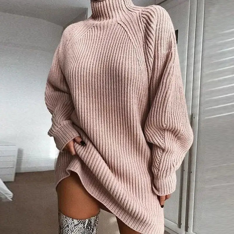 Vestido de Tricot Oversized Gola Alta Rosa em plano aproximado, com a mão puxando a barra e bota de cano alto estampada
