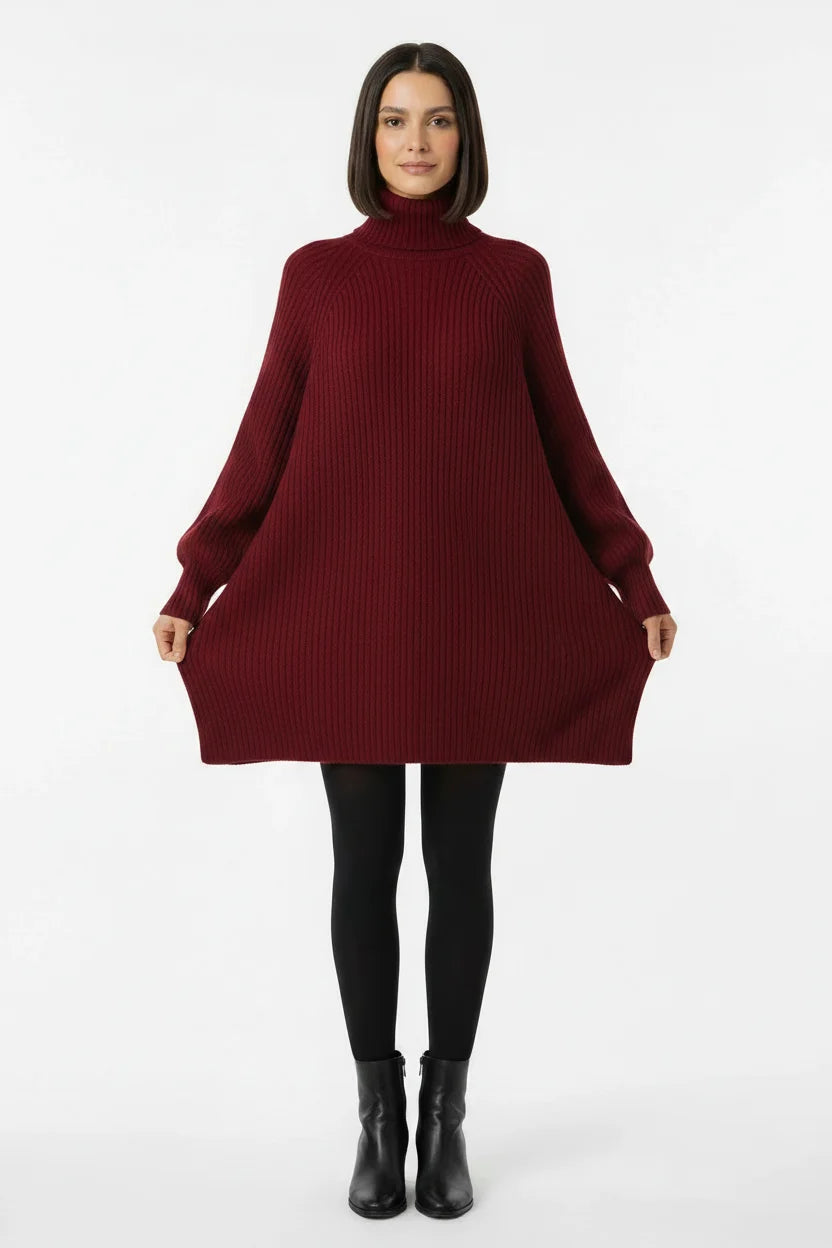 Vestido de Tricot Oversized Gola Alta Vinho com a modelo segurando as laterais, evidenciando o corte amplo