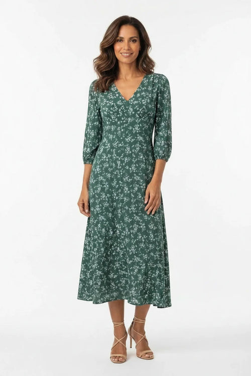 Vestido Feminino Longo Manga 3/4 Florido Verde visto de frente, com decote transpassado e sandália nude de amarração