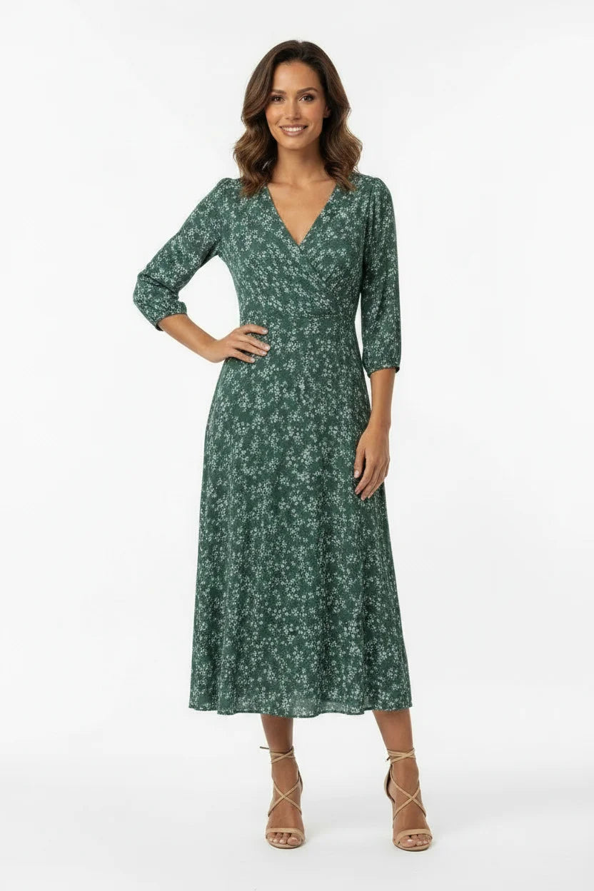 Vestido Feminino Longo Manga 3/4 Florido Verde de frente com a mão na cintura, evidenciando o transpasse do busto