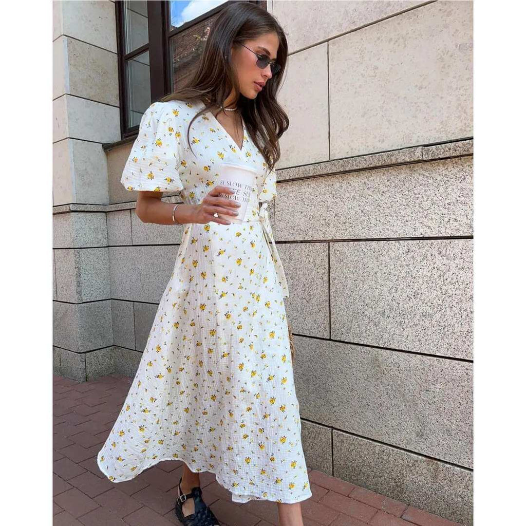 Vestido Feminino Midi Florido Amarelo em movimento na calçada, com a saia transpassada abrindo na perna