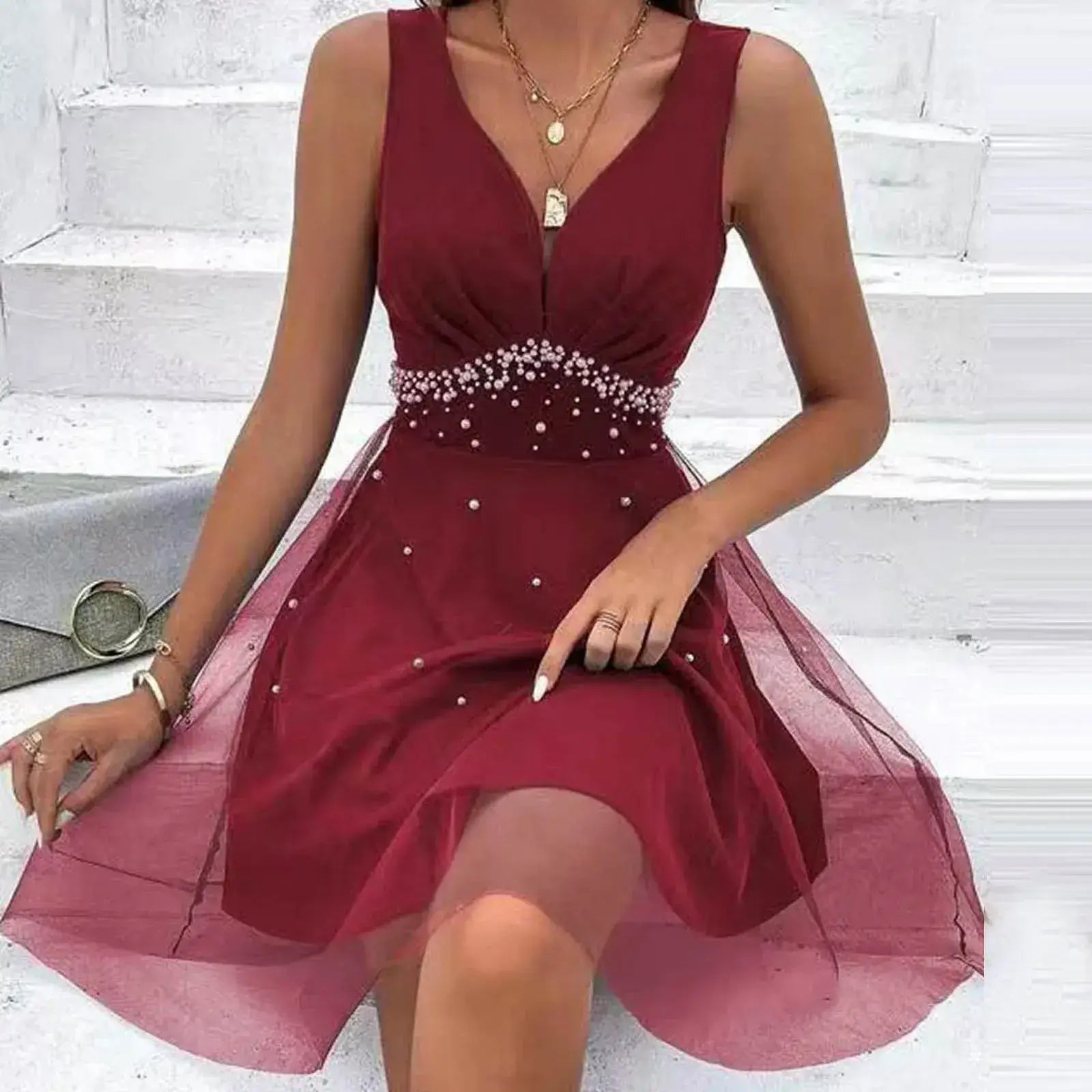 Vestido de Festa Curto Decote V Vinho, modelo sentada na escada com a saia de tule espalhada