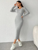 Vestido Longo de Malha Manga Longa Cinza em pose com a mão junto ao rosto, destacando a gola