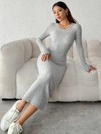 Vestido Longo de Malha Manga Longa Cinza com a modelo apoiada no sofá, mostrando o caimento da malha
