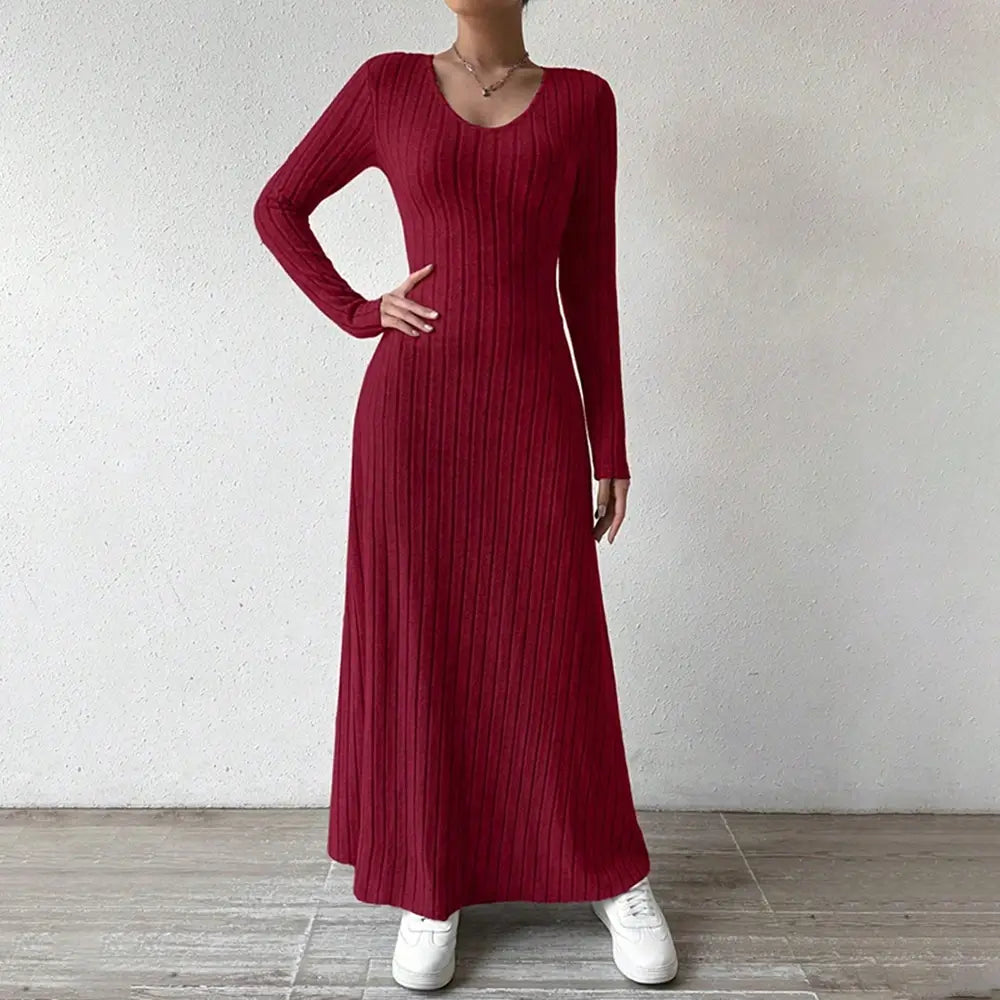 Vestido Longo de Malha Manga Longa Vermelho de frente com a mão na cintura, evidenciando a malha canelada
