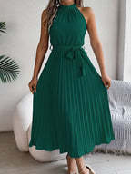 Vestido Longo Plissado Sem Mangas Anna Verde, visto de frente com laço na cintura e sandália nude