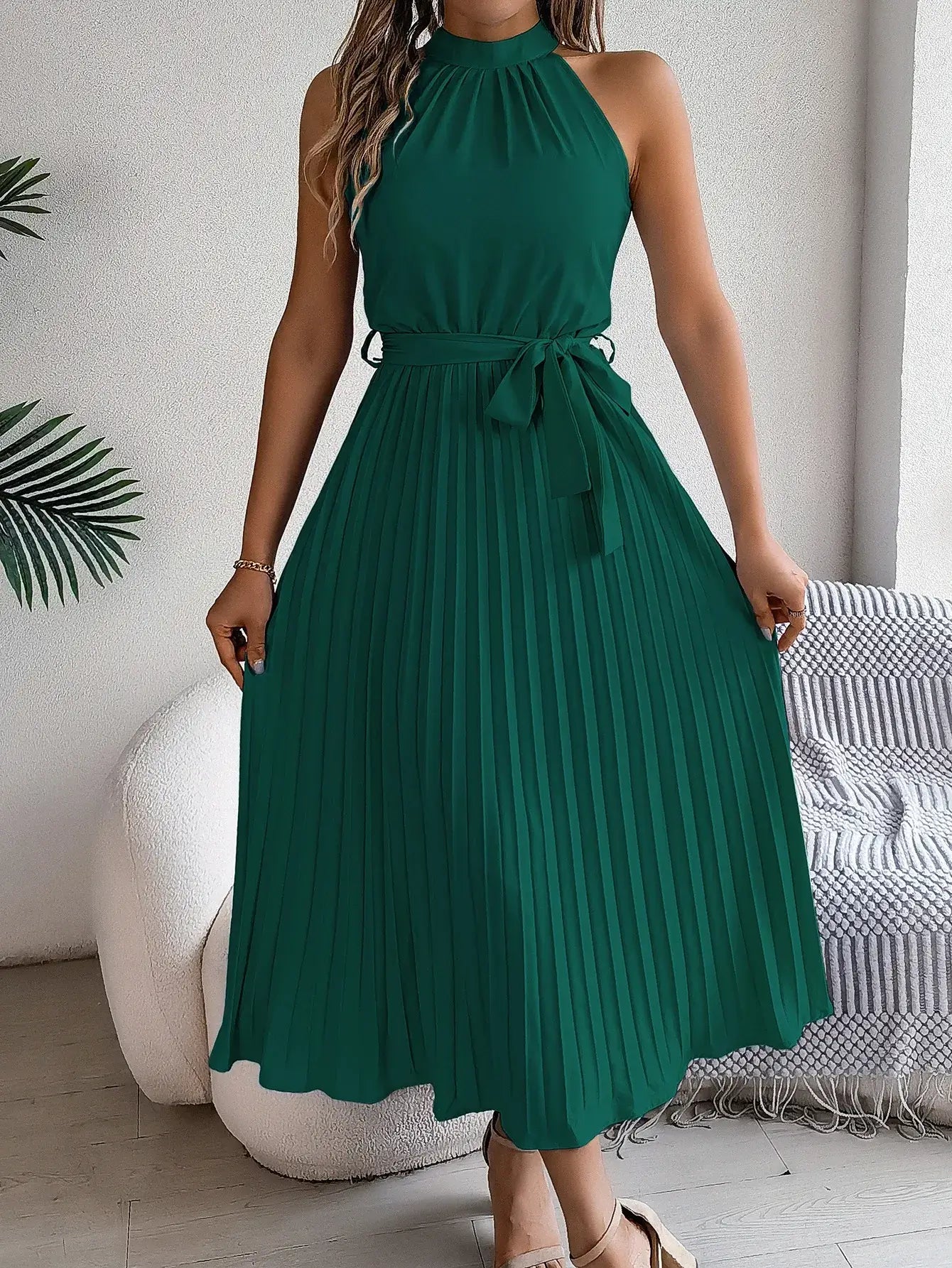 Vestido Longo Plissado Sem Mangas Anna verde, visto de frente com laço na cintura e sandália nude