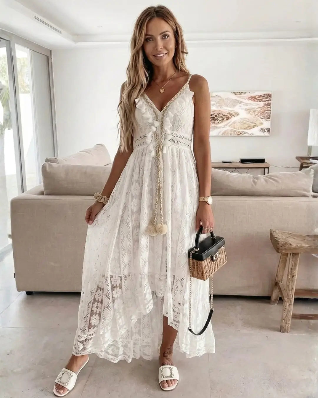 Vestido Feminino Longo de Renda Off White Estilo Boho Chic de frente em ambiente de sala, com a renda transparente em destaque