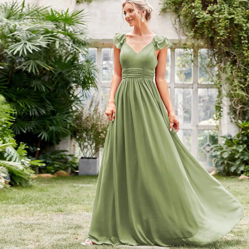 Vestido Longo Verde Fluido com Decote em V e Mangas de Babado visto de frente no jardim, com cintura franzida e saia ampla