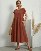 Vestido Midi Feminino Terracota em Algodão e Linho Estilo Boho com Bolsos visto de frente, com bolsa de palha e sandália rasteira