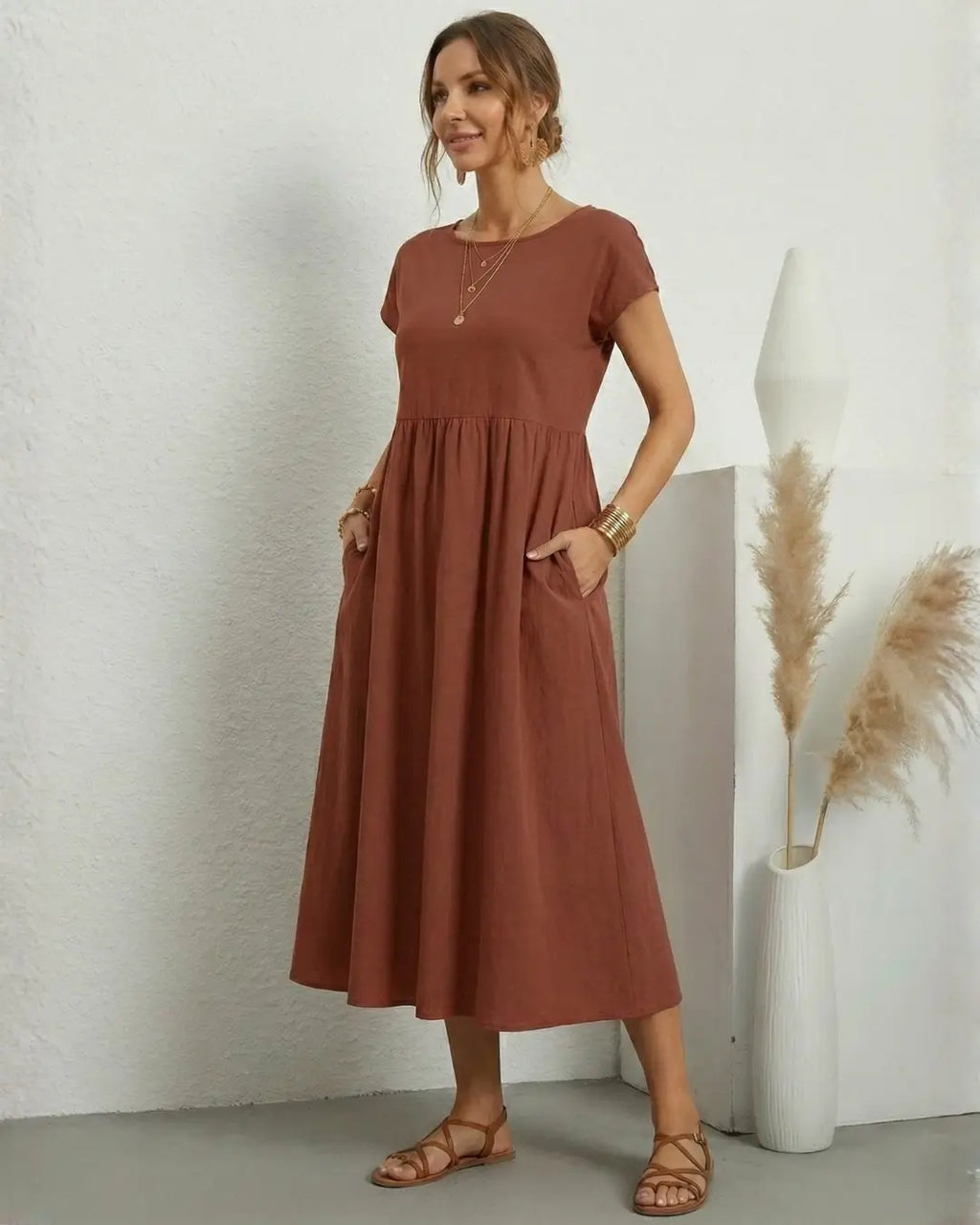 Vestido Midi Feminino Terracota em Algodão e Linho Estilo Boho com Bolsos em pose de três quartos, com as mãos nos bolsos