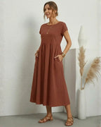 Vestido Midi Feminino Terracota em Algodão e Linho Estilo Boho com Bolsos em pose de três quartos, com as mãos nos bolsos