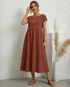 Vestido Midi Feminino Terracota em Algodão e Linho Estilo Boho com Bolsos com a modelo ajeitando o cabelo, mostrando o caimento