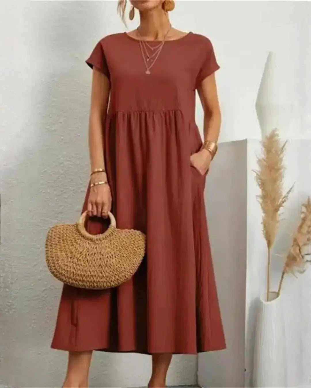 Vestido Midi Feminino Terracota em Algodão e Linho Estilo Boho com Bolsos em plano aproximado, com bolsa de palha na mão