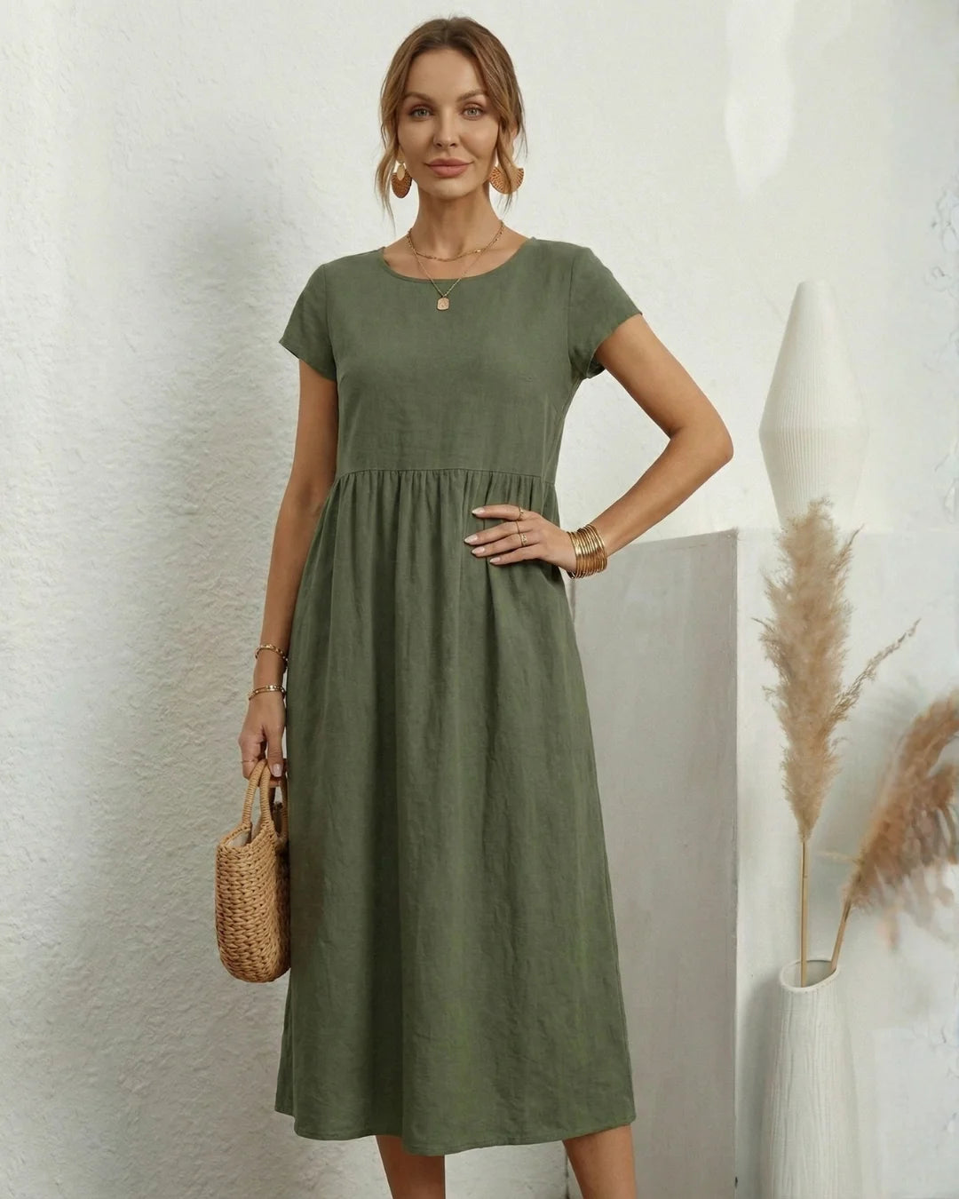Vestido Midi Verde Oliva em Linho e Algodão em plano frontal, com bolsa de palha na mão e manga curta