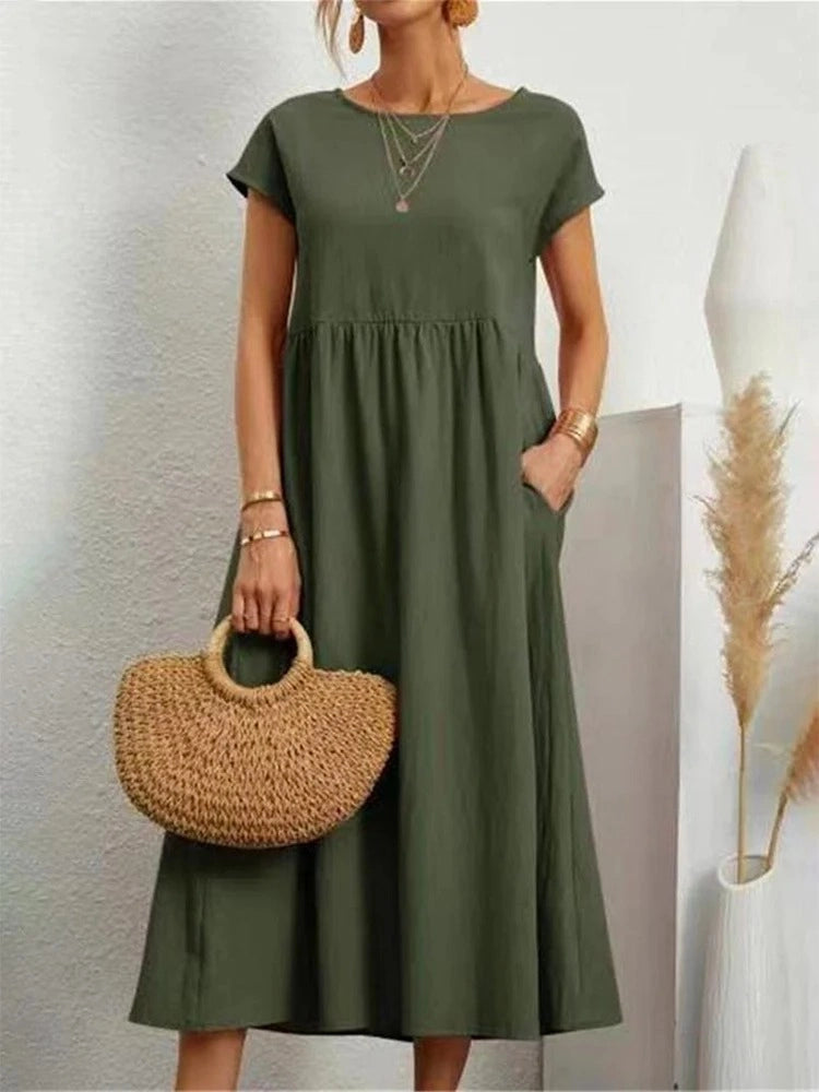 Vestido Midi Verde Oliva em Linho e Algodão de frente com a mão no bolso, destacando o decote redondo