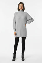 Vestido de Tricot Oversized Gola Alta Cinza de frente com a mao no quadril, mostrando o comprimento