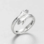 Anel Abraço em Prata 925 Hug Ring visto de frente, com o par de mãos em posição de abraço sobre o aro