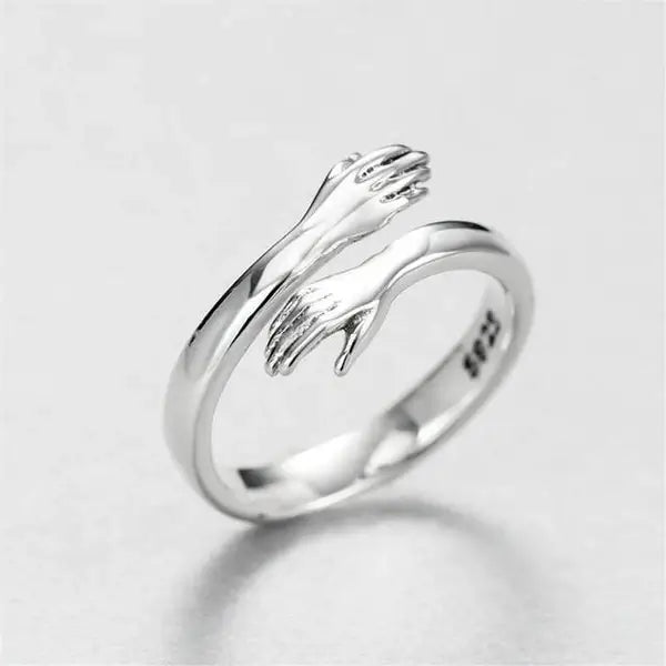 Anel Abraço em Prata 925 Hug Ring visto de frente, com o par de mãos em posição de abraço sobre o aro
